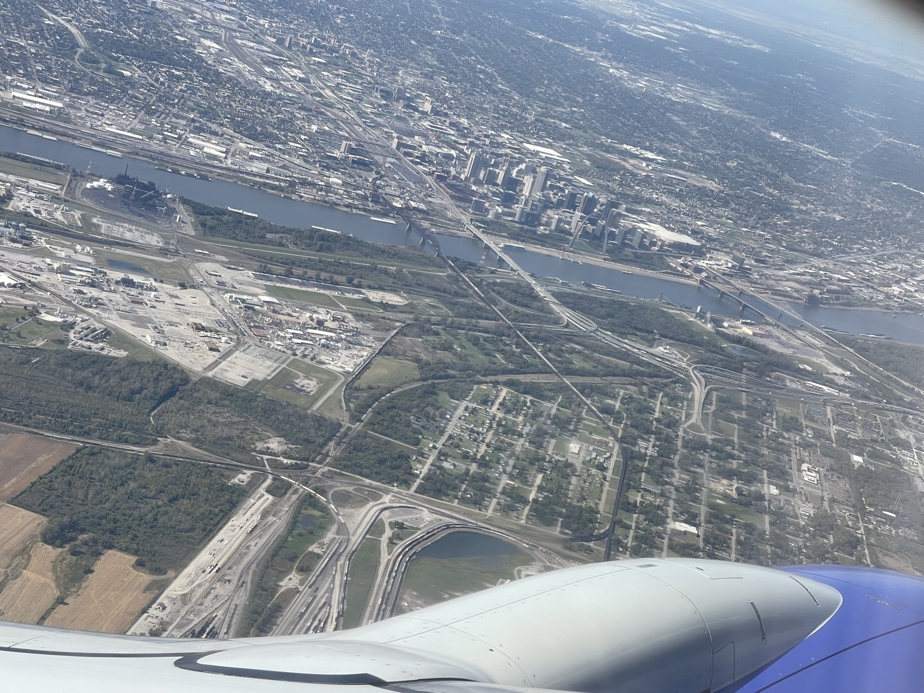 An aerial view from an airplane window shows the St Louis cityscape with the Mississippi River running through it.